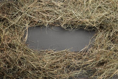 Photo of Frame made of dried hay on grey wooden table, top view. Space for text