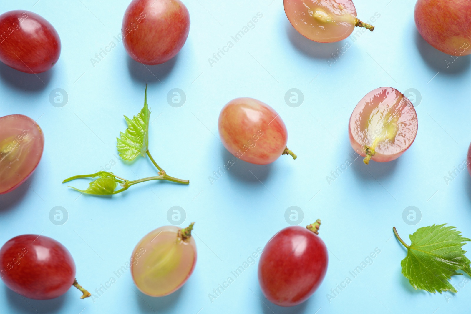 Photo of Flat lay composition with fresh ripe juicy grapes on light blue background