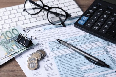 Photo of Tax accounting. Calculator, documents, money, stationery and glasses on wooden table, closeup