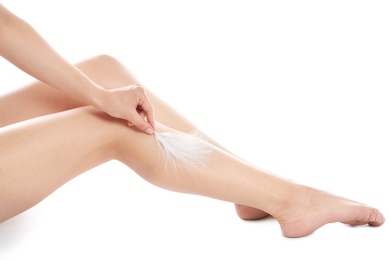 Photo of Woman touching leg with feather isolated on white, closeup. Epilation procedure