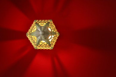 Photo of Decorative Arabic lantern on red background, top view. Space for text