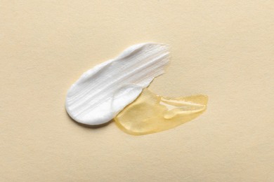 Samples of transparent gel and white cream on yellow background, flat lay