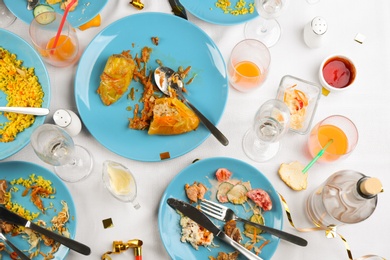 Photo of Flat lay composition with food leftovers on white tablecloth after party