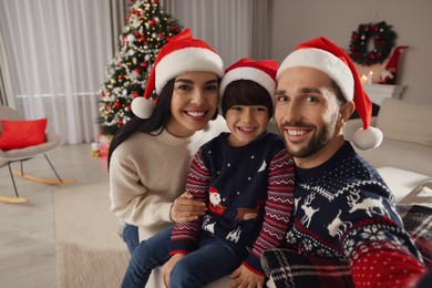Photo of Happy family in Santa hats taking selfie at home. Christmas celebration