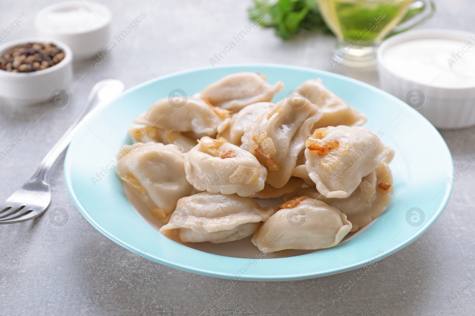 Photo of Delicious dumplings (varenyky) with potatoes and onion served on grey table