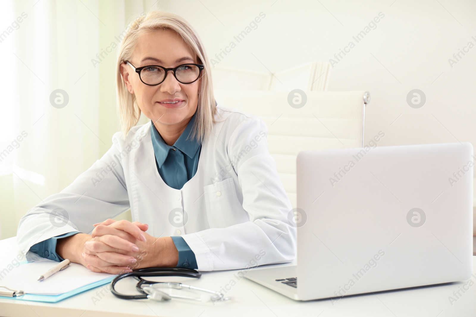 Photo of Portrait of mature female doctor in white coat at workplace