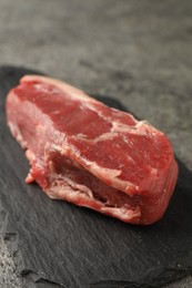 Piece of raw beef meat on grey table, closeup