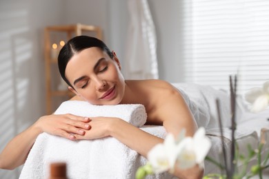 Photo of Beautiful woman relaxing on massage table in spa salon