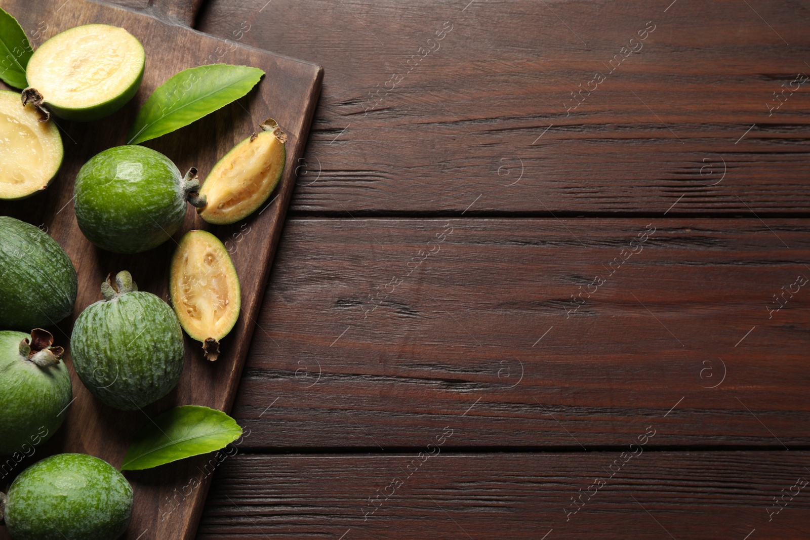 Photo of Flat lay composition with fresh green feijoa fruits on wooden table, space for text