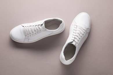 Photo of Pair of stylish white sneakers on grey background, top view