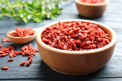 Photo of Bowl of dried goji berries on wooden table, closeup. Healthy superfood