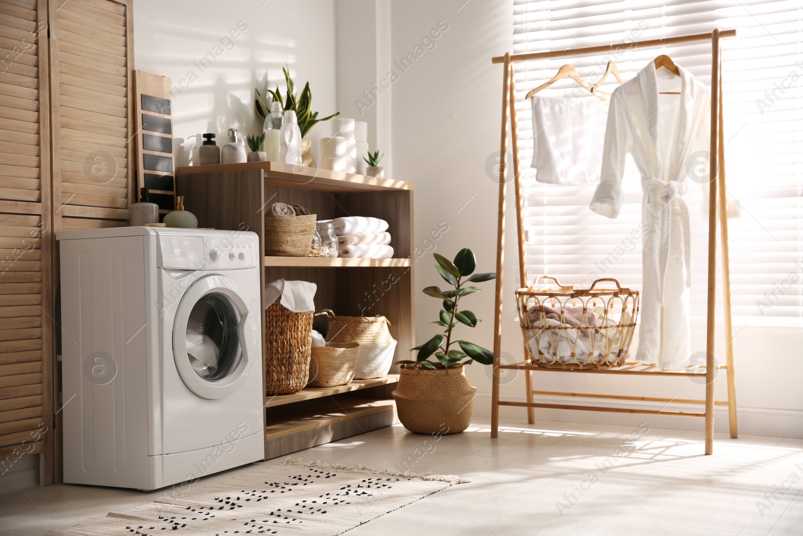 Photo of Modern washing machine and shelving unit in laundry room interior