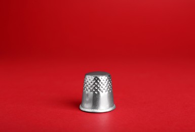 Photo of Silver thimble on red background. Sewing accessory