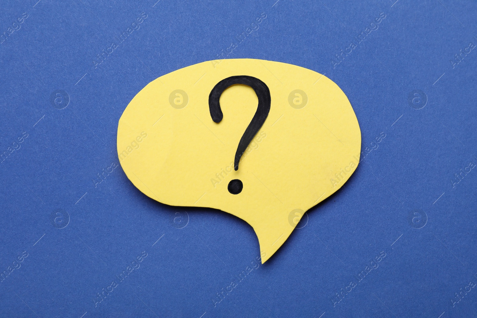 Photo of Paper speech bubble with question mark on blue background, top view