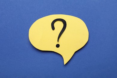Paper speech bubble with question mark on blue background, top view