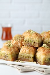 Photo of Delicious fresh baklava with chopped nuts on white table, closeup. Eastern sweets