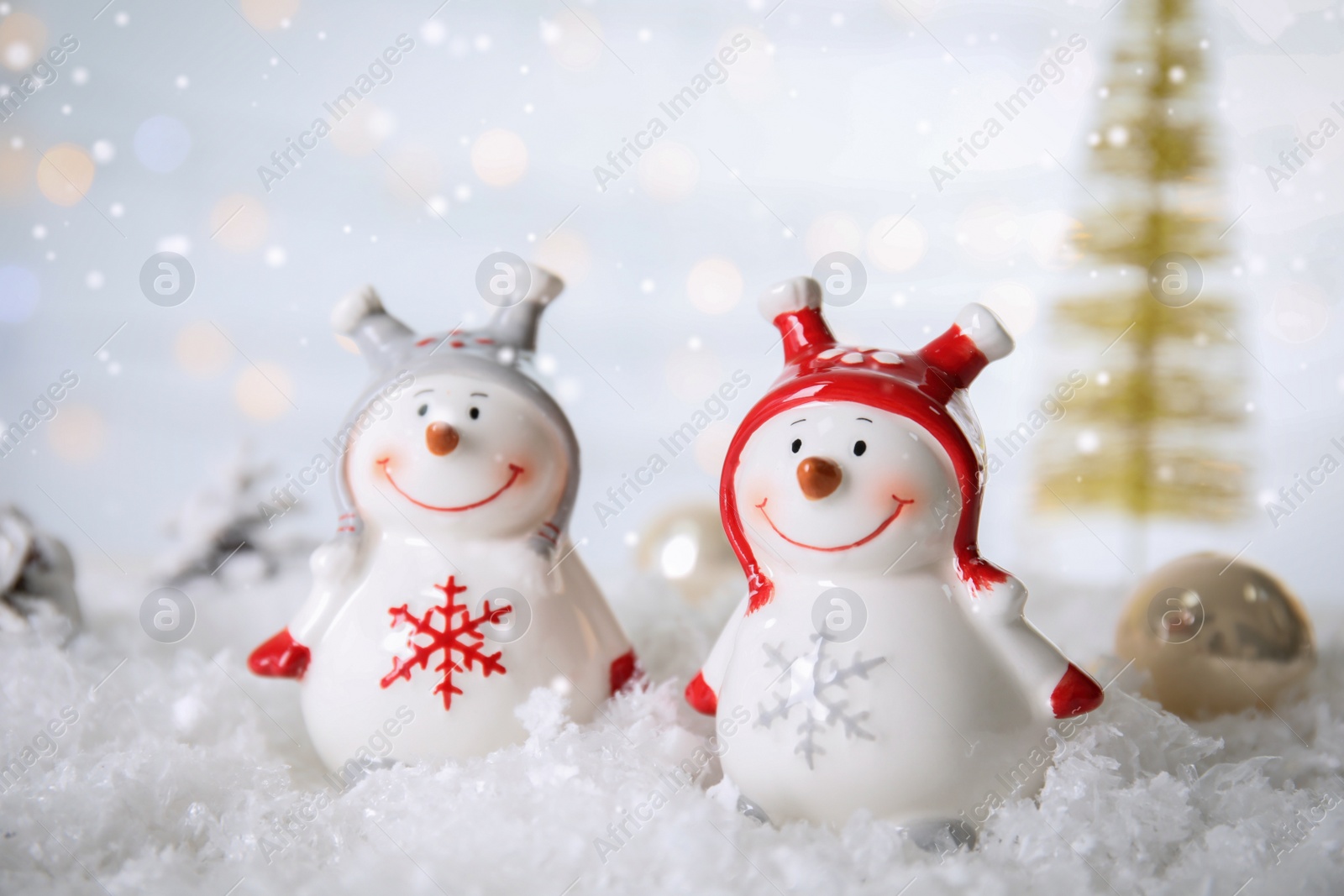 Photo of Christmas composition with decorative snowmen on artificial snow against blurred festive lights