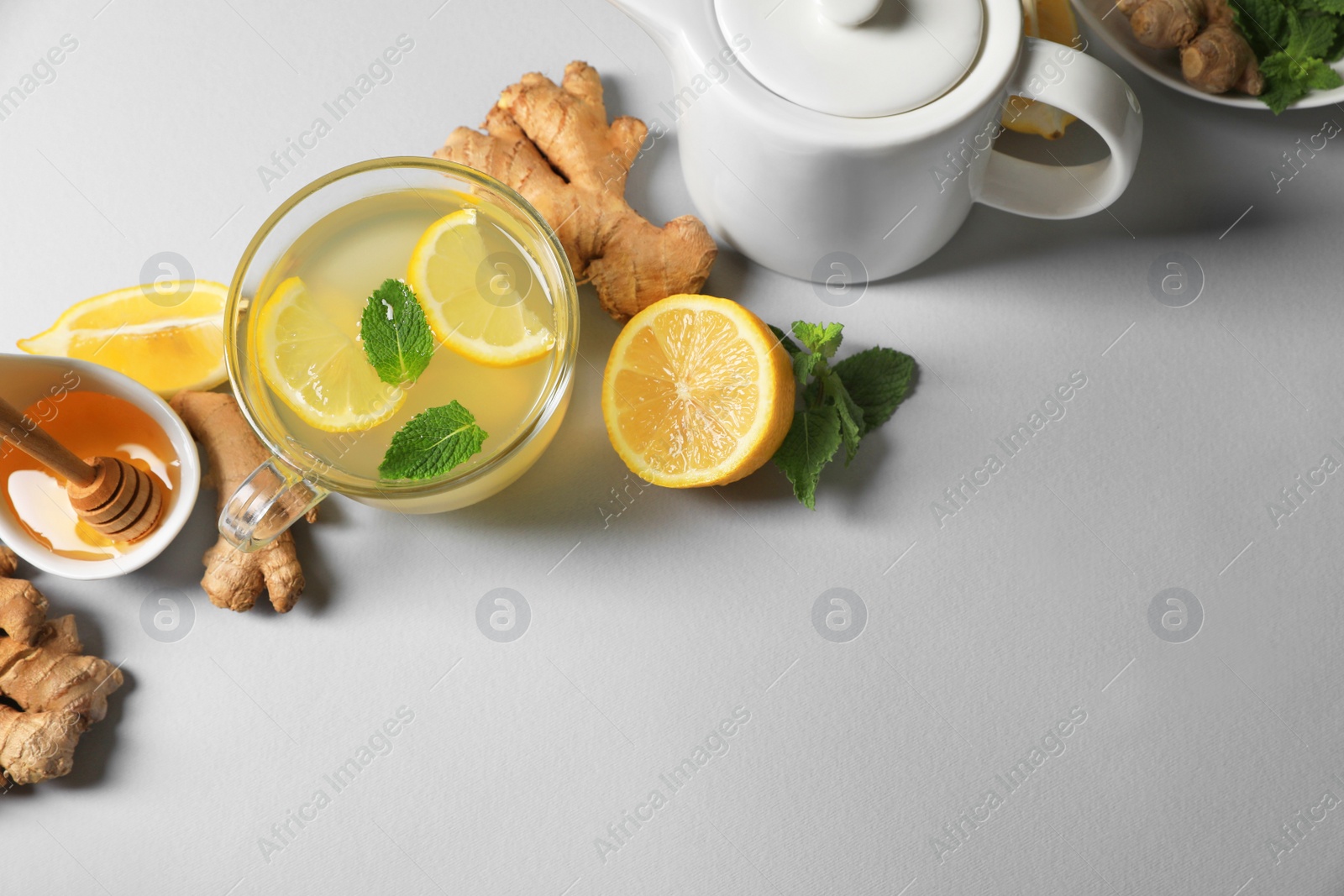 Photo of Delicious ginger tea and ingredients on light grey background, flat lay. Space for text