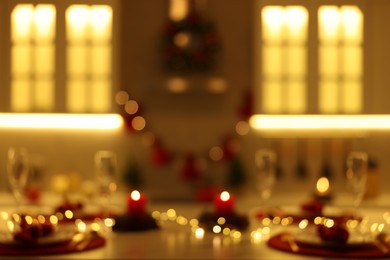 Photo of Blurred view of Christmas table setting with burning candles in kitchen