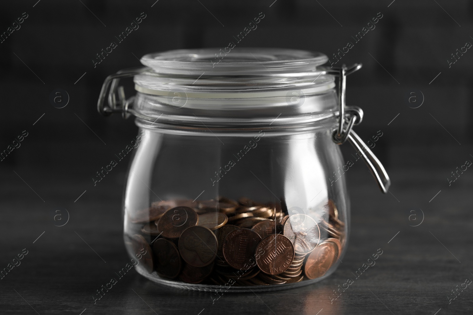 Photo of Glass jar with coins on grey table, closeup