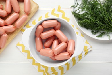 Delicious sausages and dill on white wooden table, flat lay