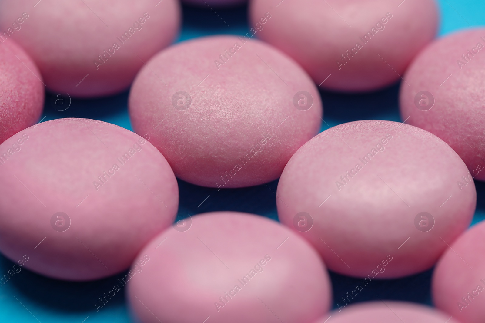 Photo of Pink bubble gums on blue background, closeup