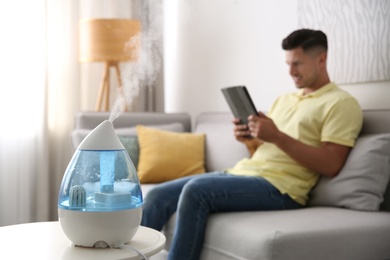 Photo of Modern air humidifier and blurred man on background