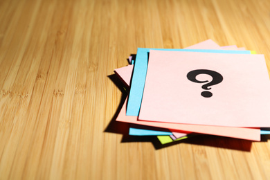 Photo of Paper cards with question mark on wooden background, closeup. Space for text