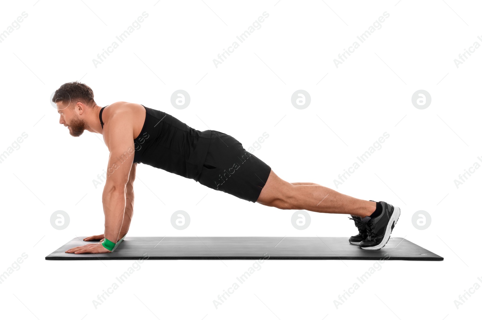 Photo of Young man exercising with elastic resistance band on fitness mat against white background