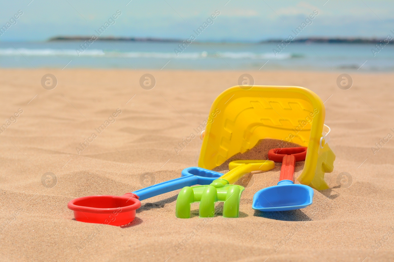 Photo of Set of colorful beach toys on sand near sea