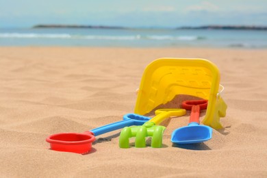 Photo of Set of colorful beach toys on sand near sea