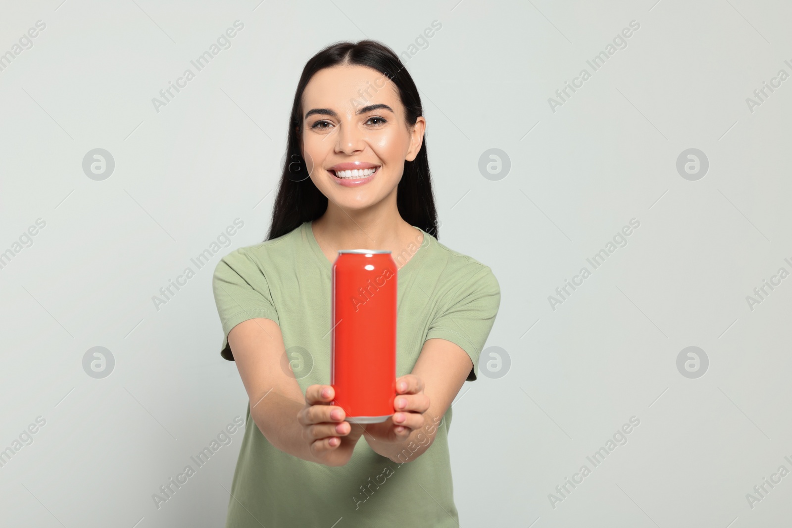 Photo of Beautiful happy woman holding red beverage can on light grey background