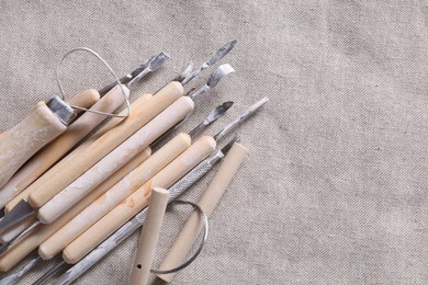 Photo of Set of different clay crafting tools on grey fabric, top view. Space for text