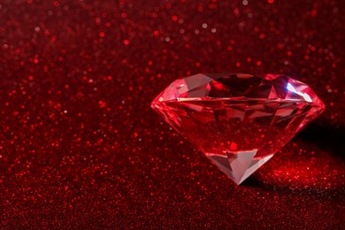 Photo of Beautiful shiny diamond on red glitter background. Space for text