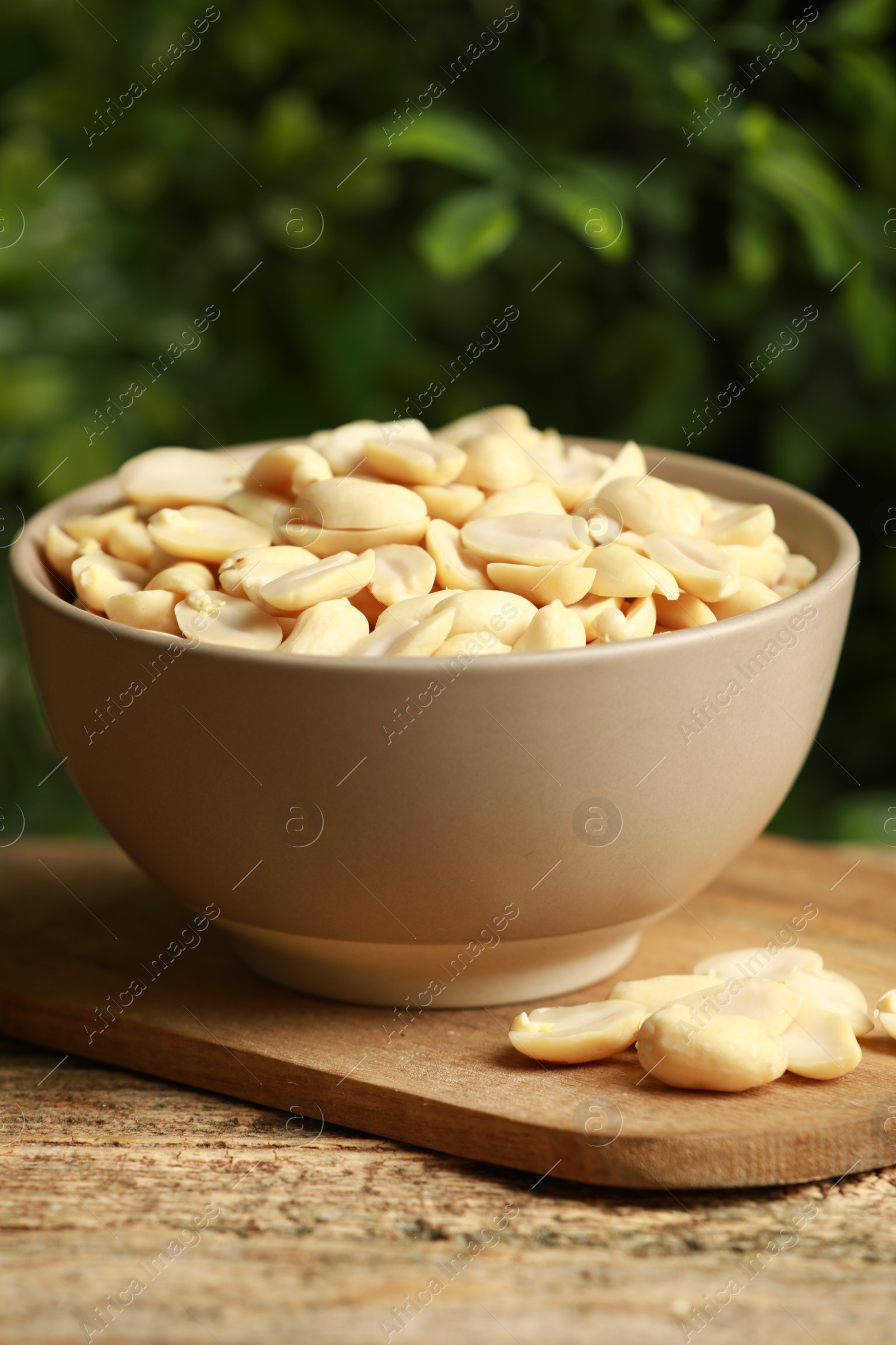 Photo of Fresh peanuts in bowl on wooden table against blurred background