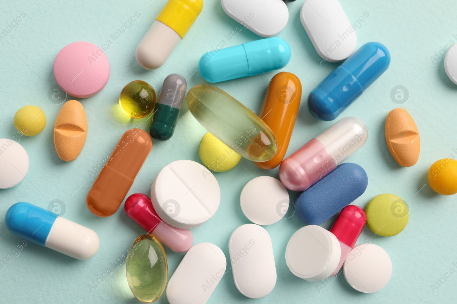 Photo of Pile of different pills on mint background, flat lay