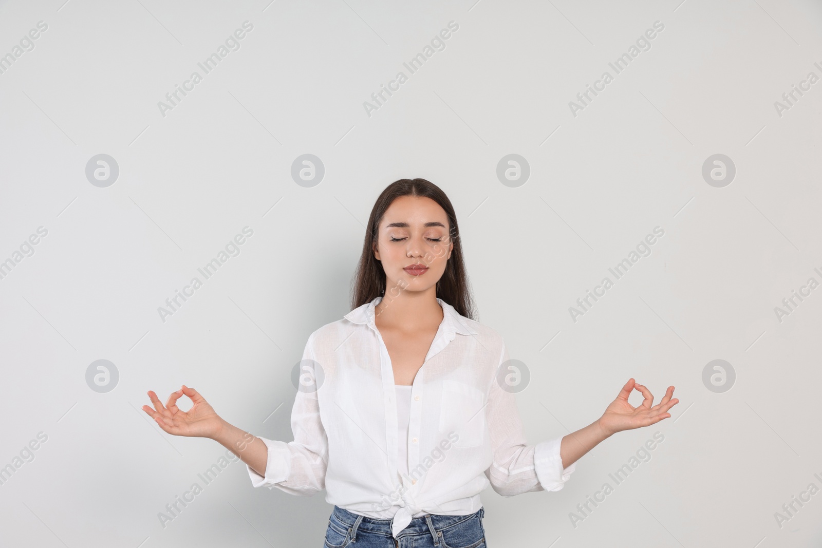 Photo of Find zen. Beautiful young woman meditating on white background