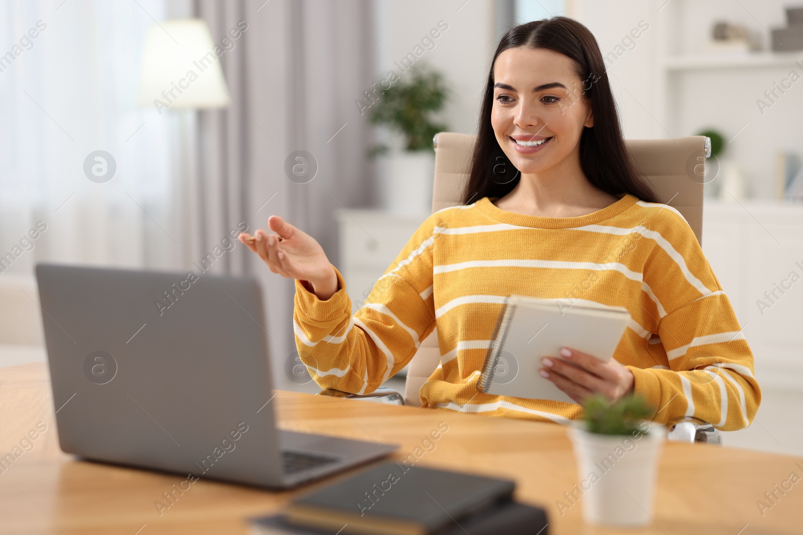 Photo of Young woman using video chat during webinar at table in room