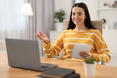 Young woman using video chat during webinar at table in room