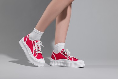 Photo of Woman wearing red classic old school sneakers on light gray background, closeup