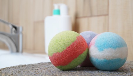 Photo of Colorful bath bombs on wicker mat in bathroom, closeup. Space for text