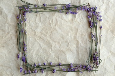 Photo of Frame of beautiful lavender flowers on white crumpled paper, flat lay. Space for text