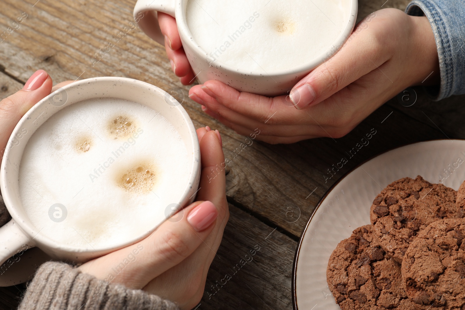 Photo of Women having coffee break at wooden table, closeup