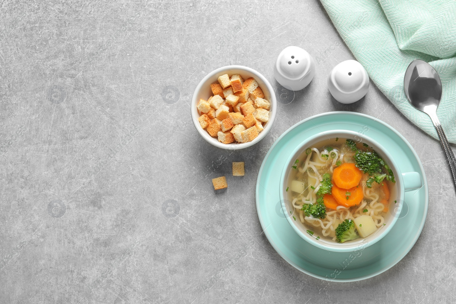 Photo of Dish of fresh homemade vegetable soup served on grey table, flat lay. Space for text