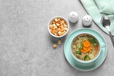 Photo of Dish of fresh homemade vegetable soup served on grey table, flat lay. Space for text