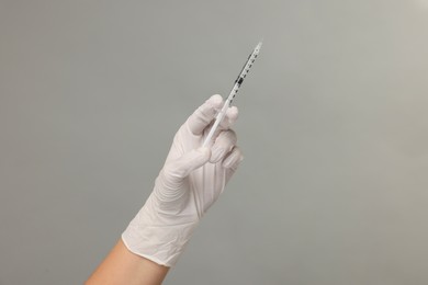 Photo of Doctor holding medical syringe on grey background, closeup