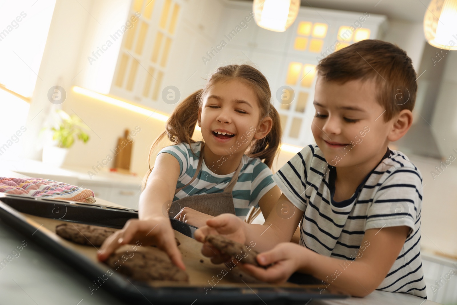 Photo of Cute little children with fresh delicious cookies in kitchen. Cooking together