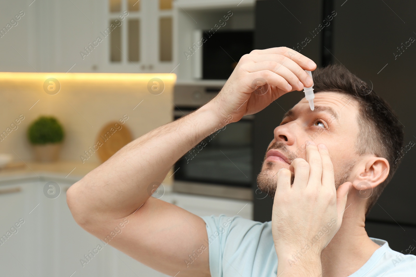 Photo of Man using drops for eyes at home