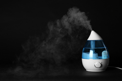 Modern air humidifier on black background. Space for text