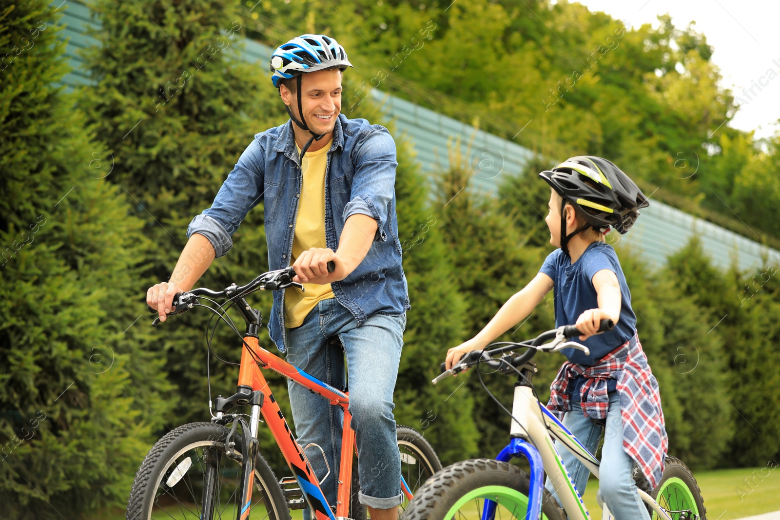 Photo of Dad and son riding modern bicycles outdoors